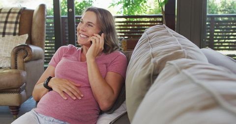 Cheerful Pregnant Woman Talking on Phone Relaxing at Home