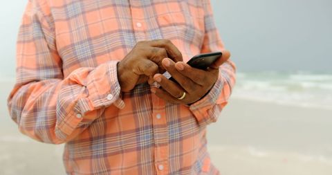 Senior Man Texting on Beach with Mobile Phone