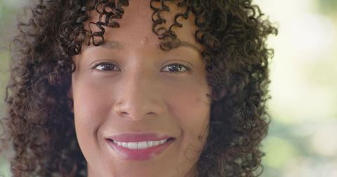 Smiling african american woman with tight curly hair and nose stud outdoor headshot