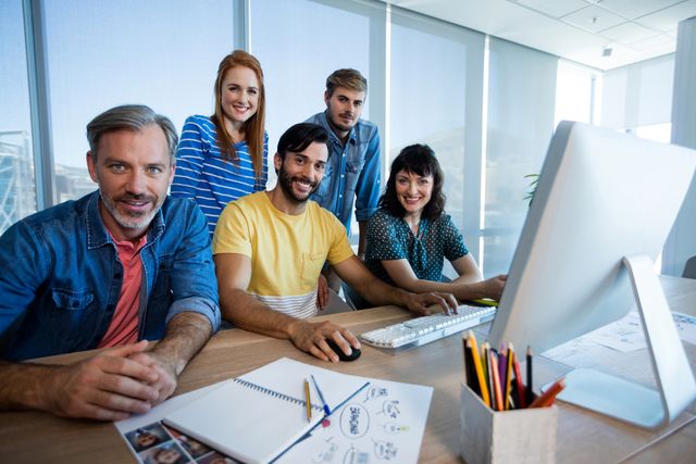 Portrait of creative business team working together on desktop pc in office