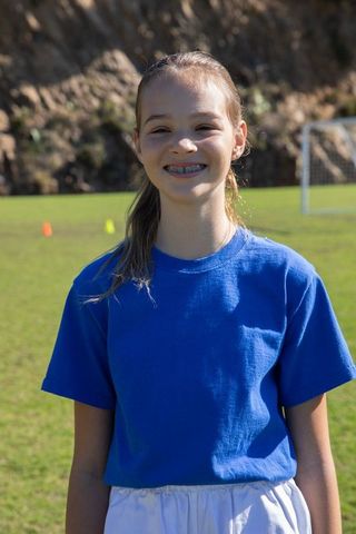 Energetic Smiling Teen Girl on Outdoor Sports Field in Blue Activewear