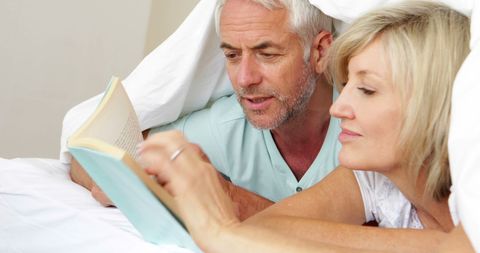 Senior Couple Cozy Reading Together in Bed