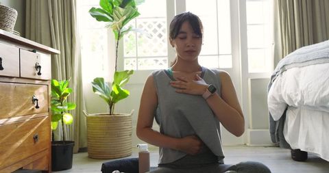 Relaxed woman practicing breathing exercise in tranquil bedroom setting