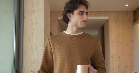 Man in Cozy Sweater Holding Mug in Modern Pine Interior