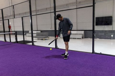 Young athlete practicing paddle drill on purple indoor court wearing cap and training gear