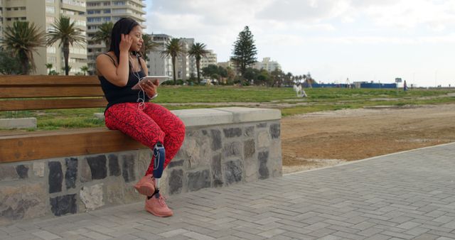 Young woman listening to music on tablet while relaxing on park bench - Download Free Stock Images Pikwizard.com