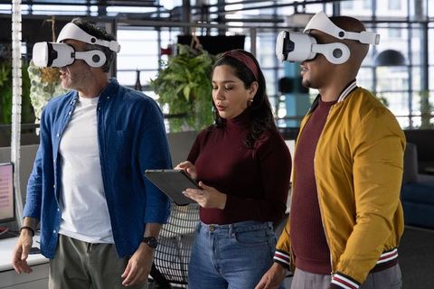 Diverse team testing virtual reality headsets while colleague controlling demo on tablet