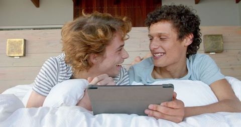 Happy Gay Couple Enjoying Tablet Time Together At Home in Cozy Setting