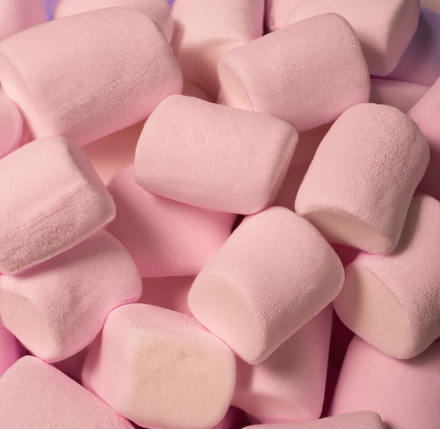 Close up of multiple pink marshmallows lying on blue background. Sweets, food and drink concept.