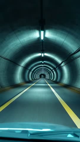 Driving through illuminated concrete tunnel from car hood perspective — vertical dashcam footage