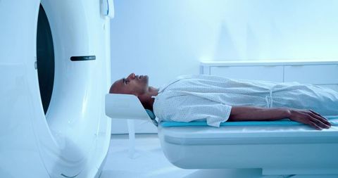 African american man undergoing mri scan on sliding scanner table in sterile radiology suite