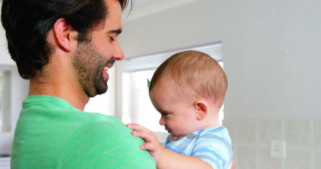 Happy father smiling and holding his baby at home - Download Free Stock Photos Pikwizard.com