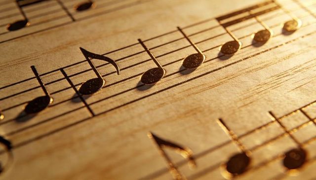 Gilded musical notes on textured manuscript close-up with warm golden light macro bokeh detail