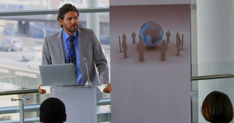Business seminar speaker presenting with laptop and world globe graphic