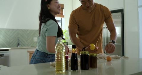 Asian couple preparing weekend brunch at modern sunlit kitchen island with fresh ingredients
