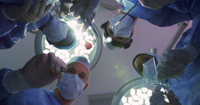 Upward view of Multi-ethnic Surgeons performing surgery in operation theater at hospital. They are interacting with each other