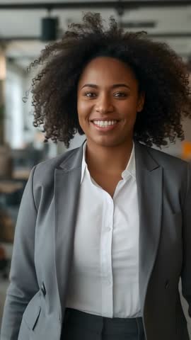 Smiling executive stepping forward and greeting camera in modern office vertical video