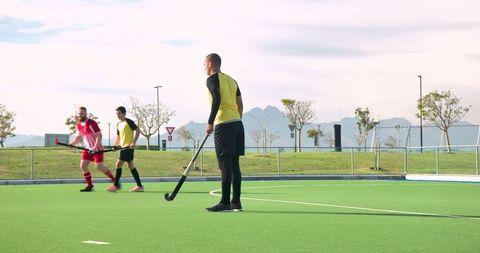 Athletic Men Playing Field Hockey in Outdoor Sports Field