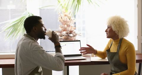 Diverse team discussing spreadsheets over coffee in cafe
