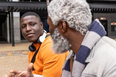 African american men sharing intergenerational conversation on urban plaza bench