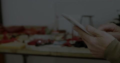 Mature woman holding tablet at workshop bench tapping screen closeup with tools and crafts