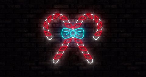 Neon candy canes on black brick wall for festive holiday celebration