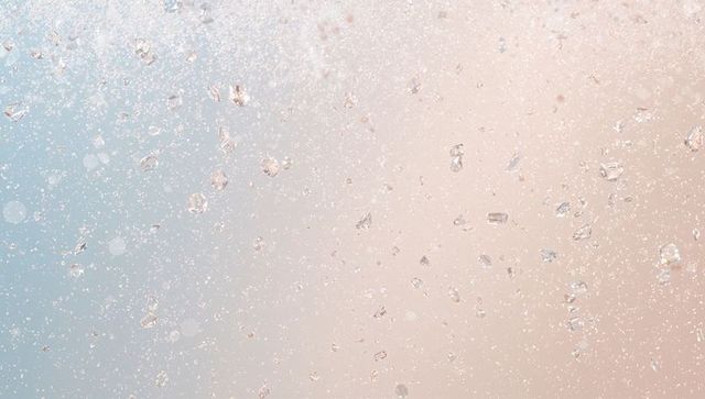 Shimmering crystal flakes scattering light across pastel bokeh backdrop for luxury design