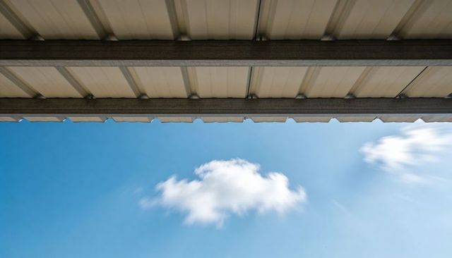 Tilting upward showing corrugated metal canopy and drifting cloud over blue sky