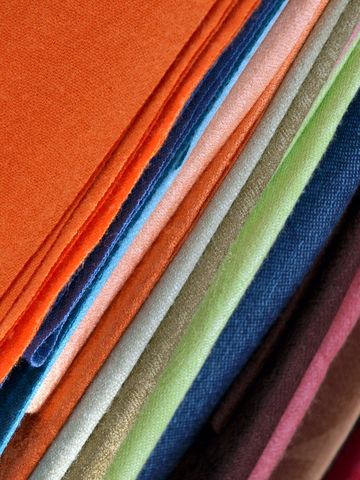 Colorful stacked fabric swatches showing varied textures vibrant textile sample close-up