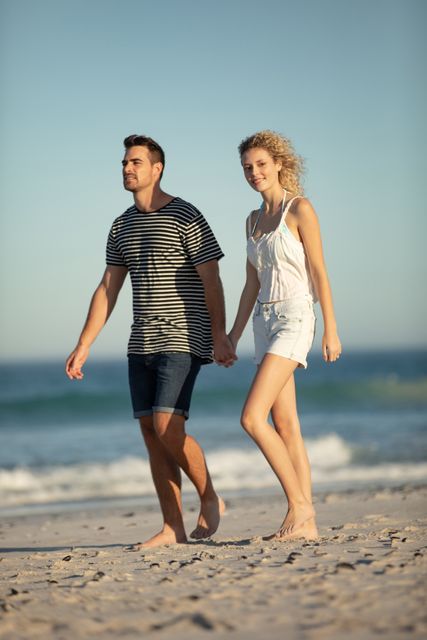 Happy Couple walking together hand in hand on the beach
