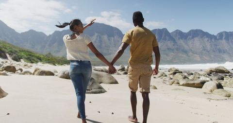 Couple walking hand-in-hand on scenic beach