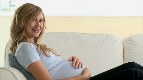 Smiling Pregnant Woman Relaxing on Sofa at Home