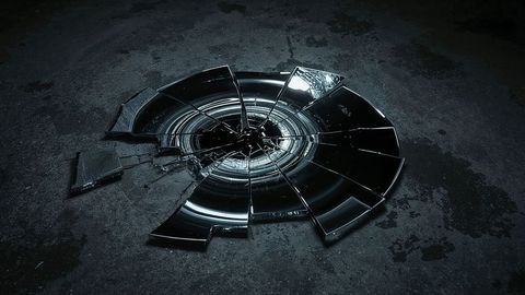 Shattered circular glass on concrete surface in dim light