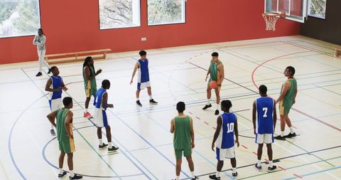 Diverse Male Basketball Team Practicing Strategies in Gymnasium