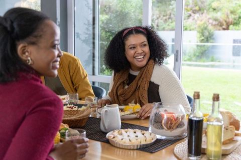 African American Friends Sharing Cozy Breakfast and Laughter at Sunlit Home Dining Table