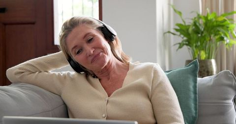 Senior Woman Relaxing with Headphones and Laptop at Cozy Home