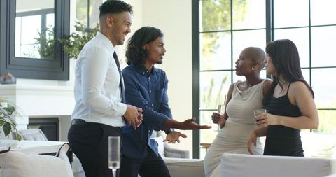 Diverse professionals socializing with champagne in living room wearing cocktail attire
