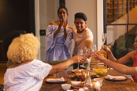 Friends raising glasses for intimate candlelit dinner celebration with charcuterie