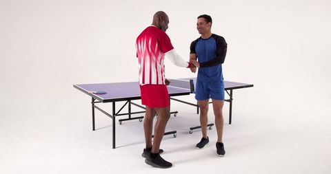 Male ping pong players shaking hands post match in studio
