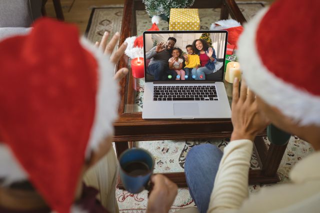Diverse couple with santa hats having video call with happy african american family. Christmas, celebration and digital composite image.