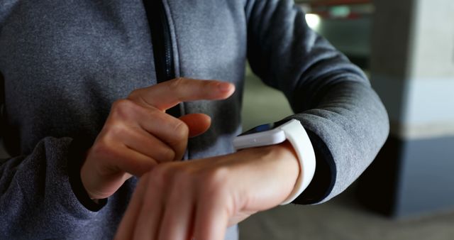 Person in an urban environment interacting with a smartwatch. Ideal for illustrating themes of modern technology, fitness tracking, and wearable devices used for health and exercise. Perfect for articles, advertisements, and social media campaigns related to health technology, digital fitness, and contemporary lifestyles.