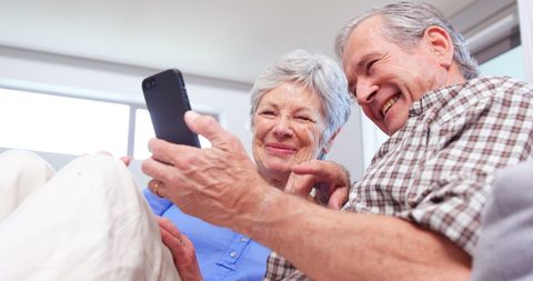 Joyful Elderly Couple Sharing Smartphone Moments