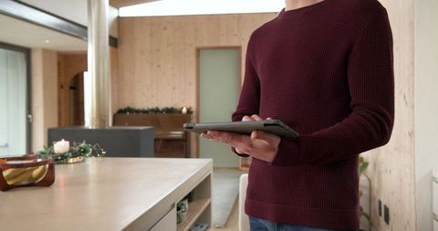 Woman Using Tablet in Cozy Open-Plan Kitchen with Wooden Panels