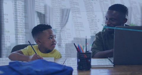 Parent helping child with homework at table using laptop, pencils and backpack