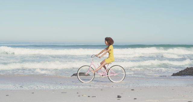 Happy biracial woman cycling on the beach and laughing. Summer, relaxation, vacation, happy time, summer time, cycling.