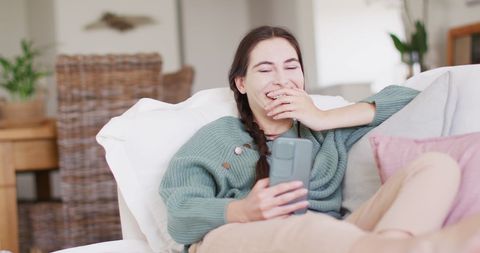 Joyful Caucasian Woman Relaxing at Home with Smartphone