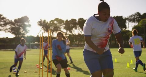 Women footballers training on brightly lit field