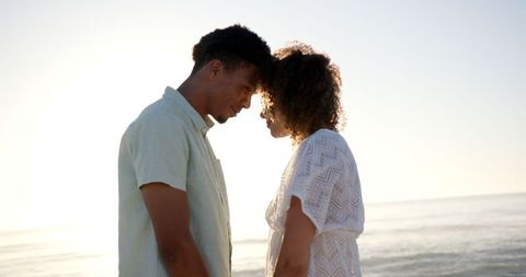 Romantic biracial couple embracing at sunset beach