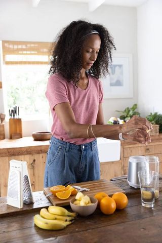 African american woman preparing fresh fruit smoothie on rustic kitchen island