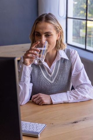 Businesswoman hydrating at office desk with focused expression